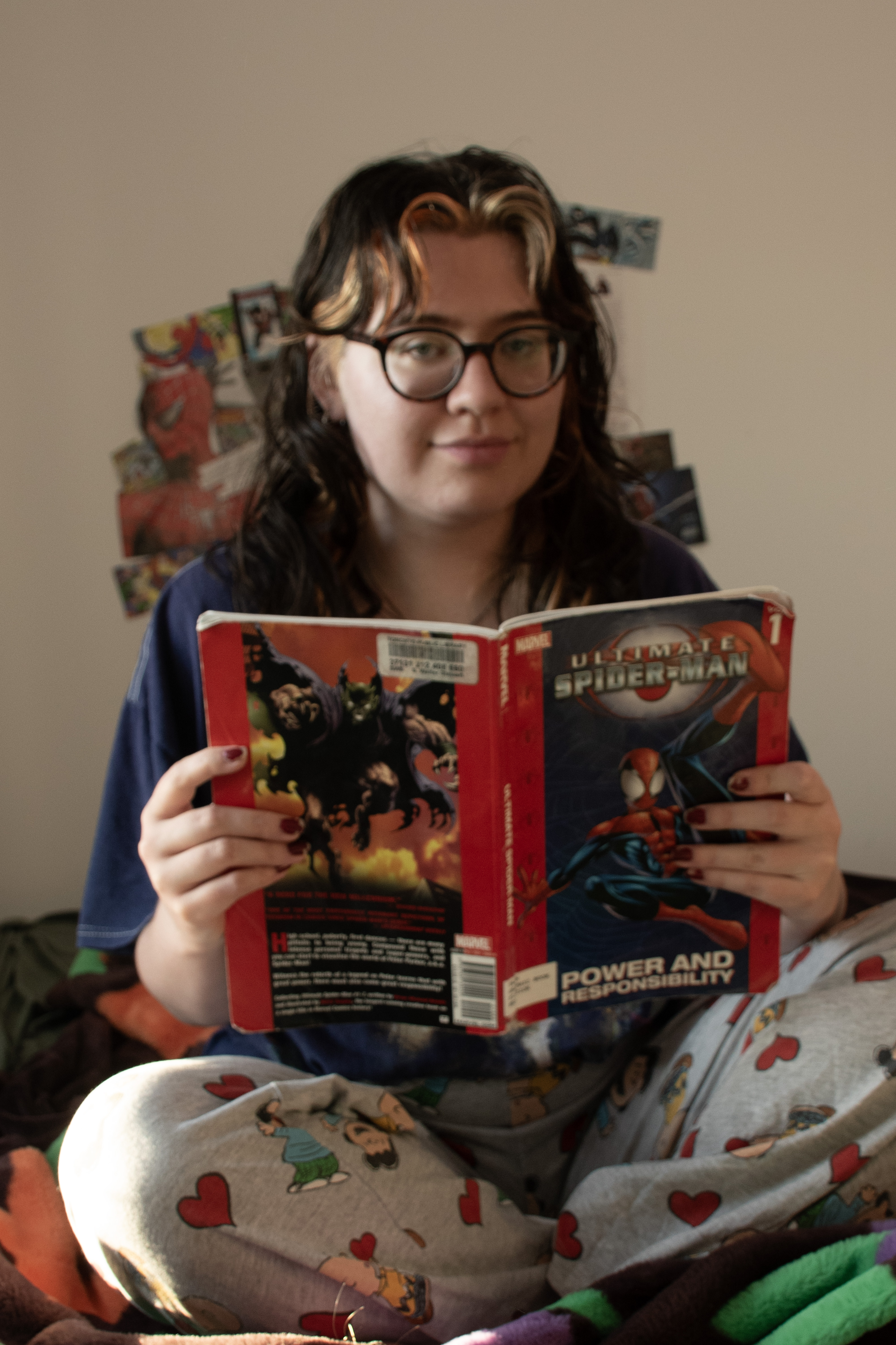 Woman sitting criss crossed on a bed reading a Spider-man comic book